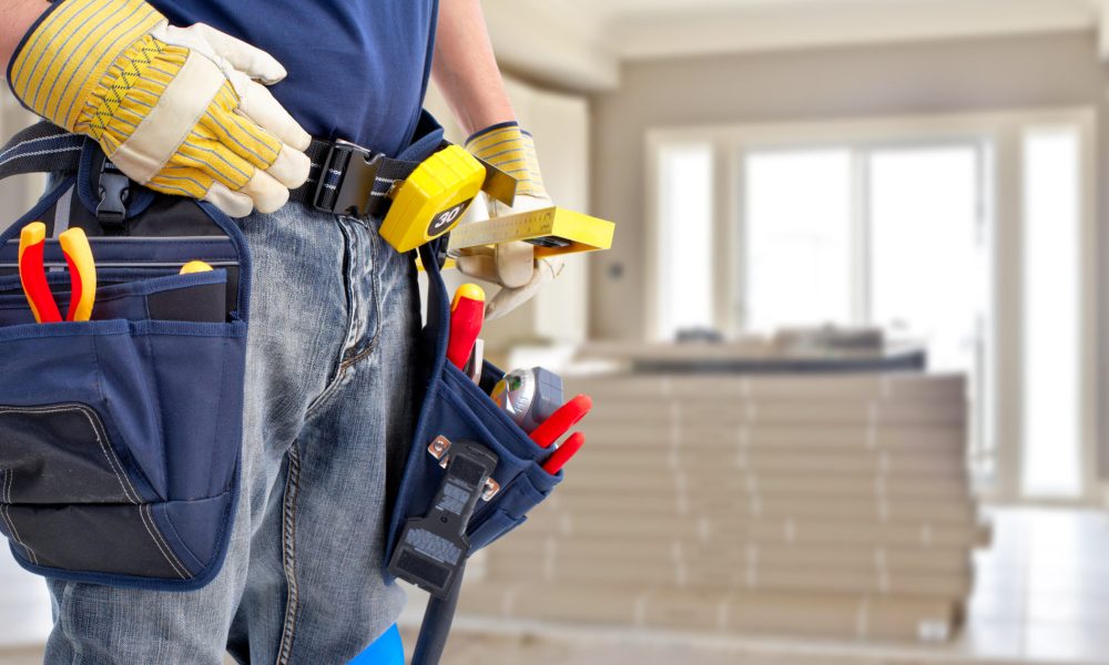 Builder handyman with construction tools. House renovation background.